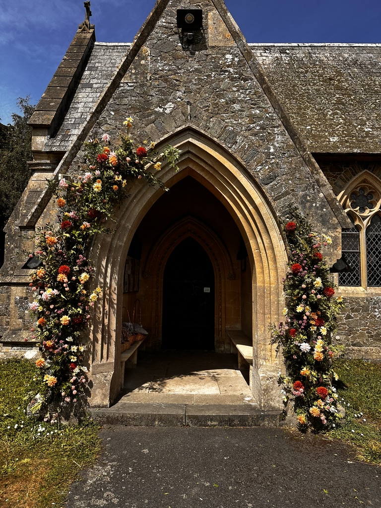 Stone church entrance framed with colourful wedding flowers