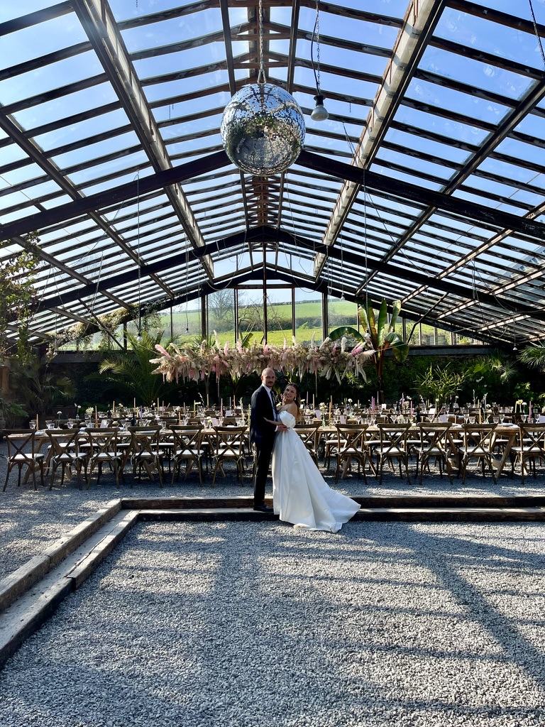 Newly married couple standing beneath the disco ball in the Glasshouse