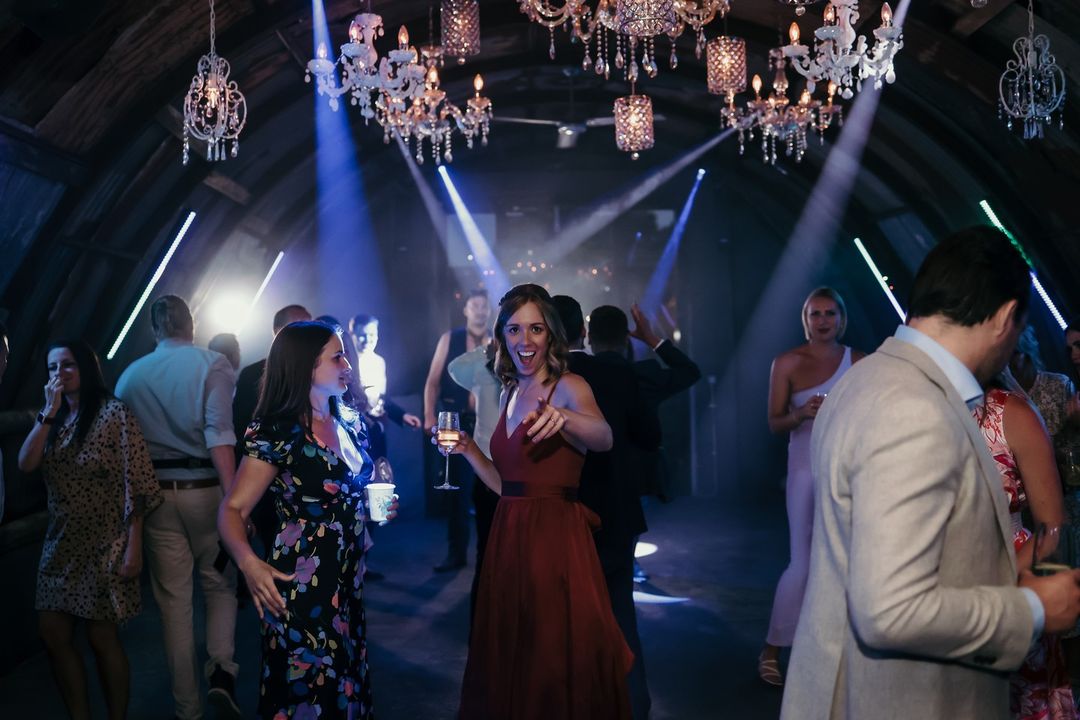 Wedding guests enjoying the dance floor beneath chandeliers