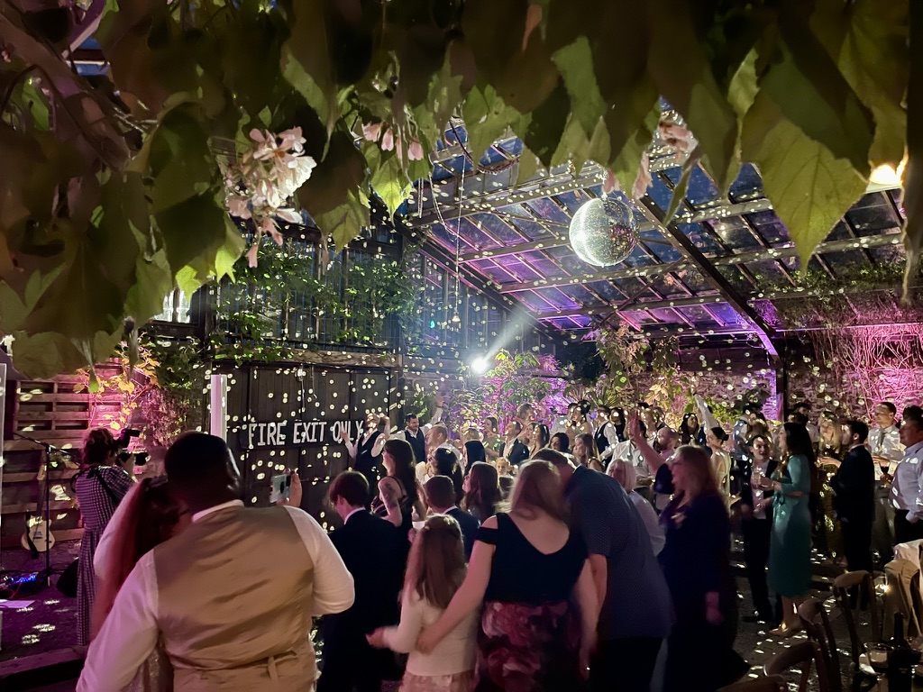 Guests celebrating beneath colourful lighting and a mirror ball