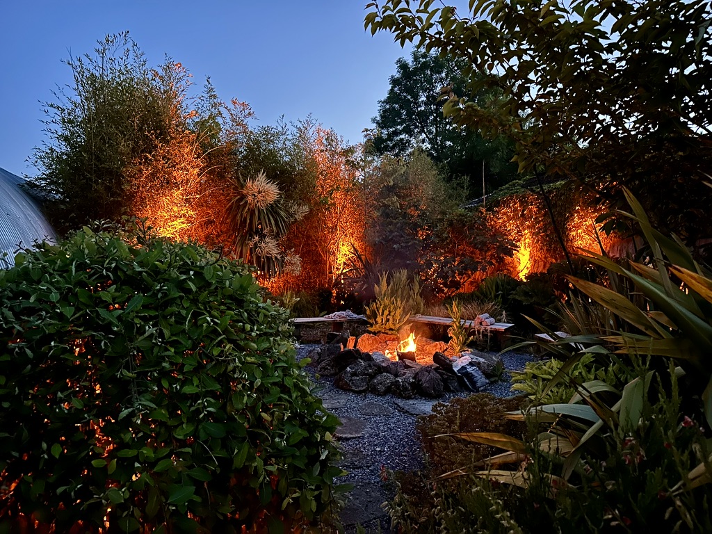 Warm lighting around the ANRÁN fire pit and gardens
