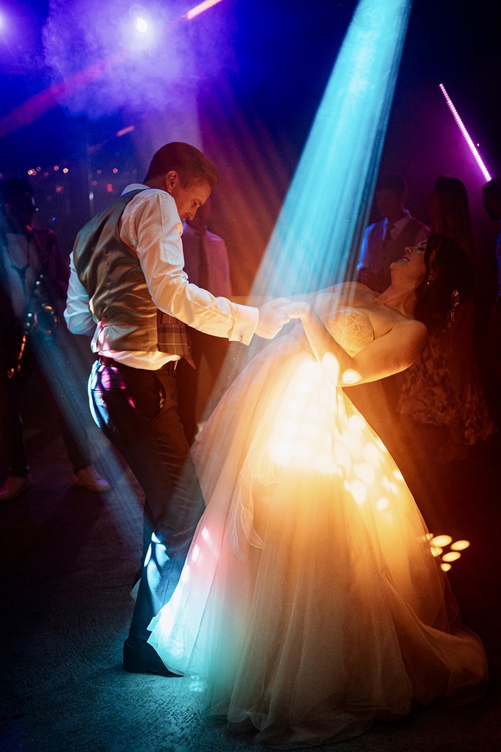 A newly married couple dancing beneath colourful DIS2GO lighting