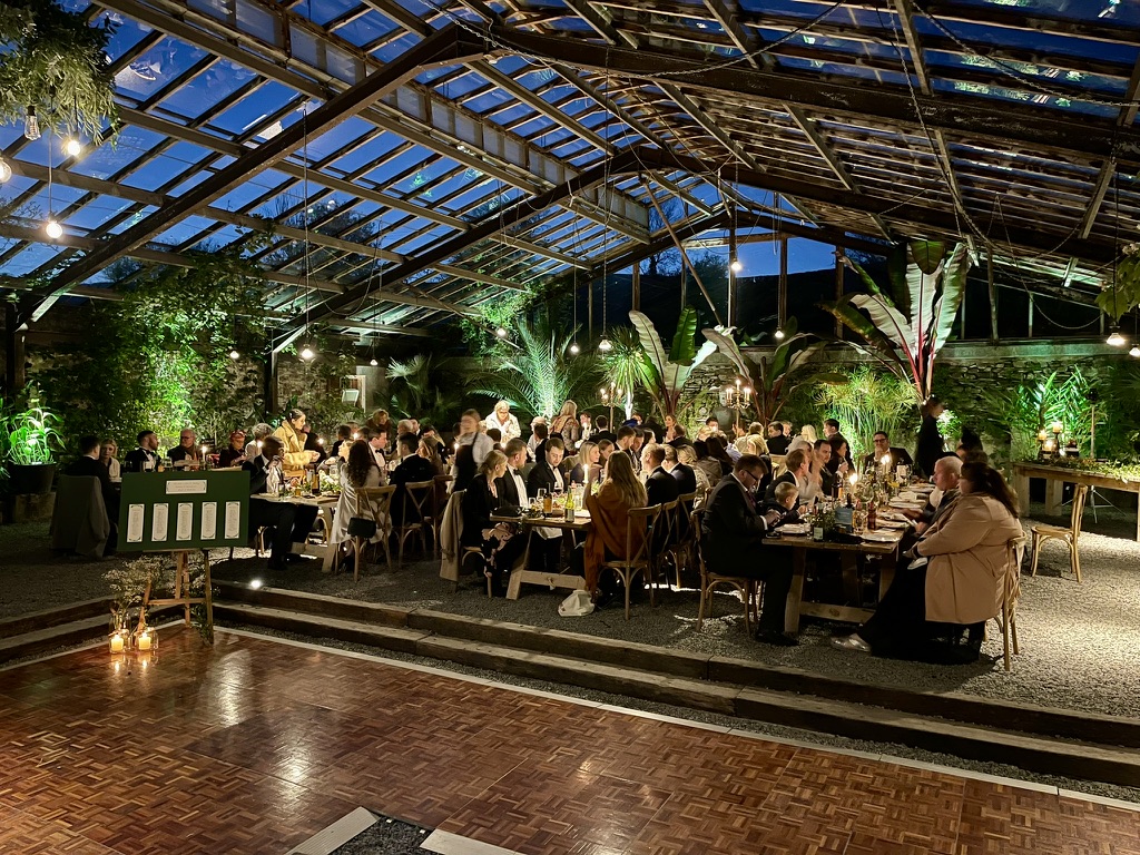 Guests dining in the illuminated Glasshouse at blue hour