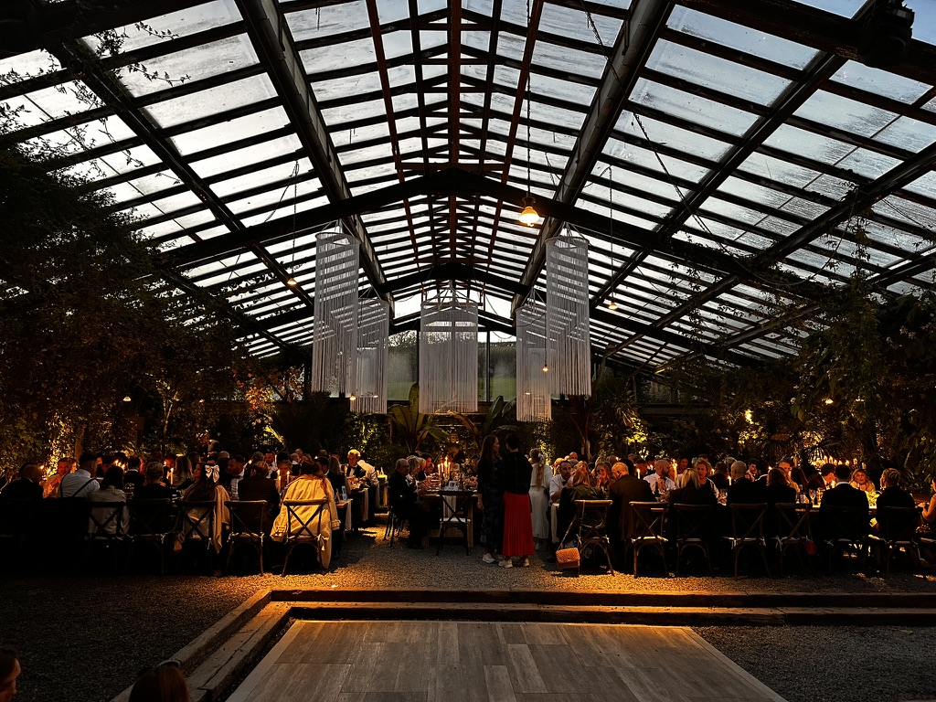 Wedding guests dining in the illuminated ANRÁN Glasshouse