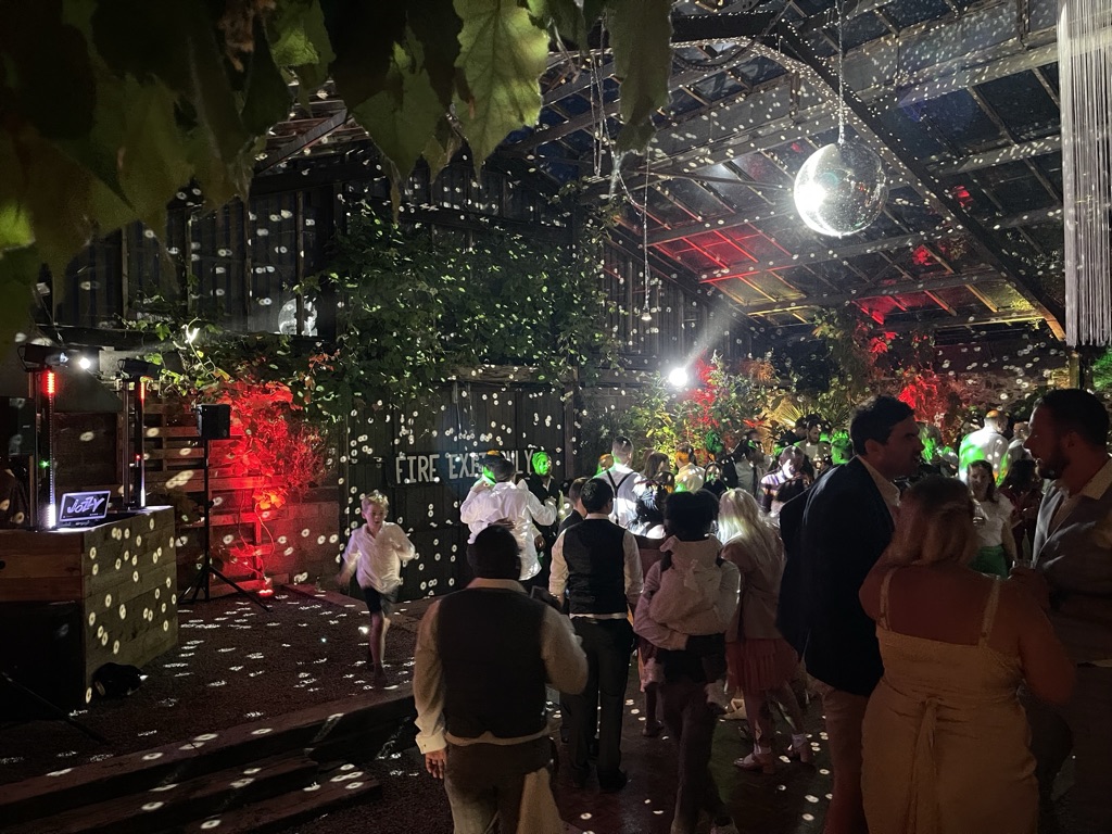 Busy dance floor in the Glasshouse with red lighting and mirror-ball reflections