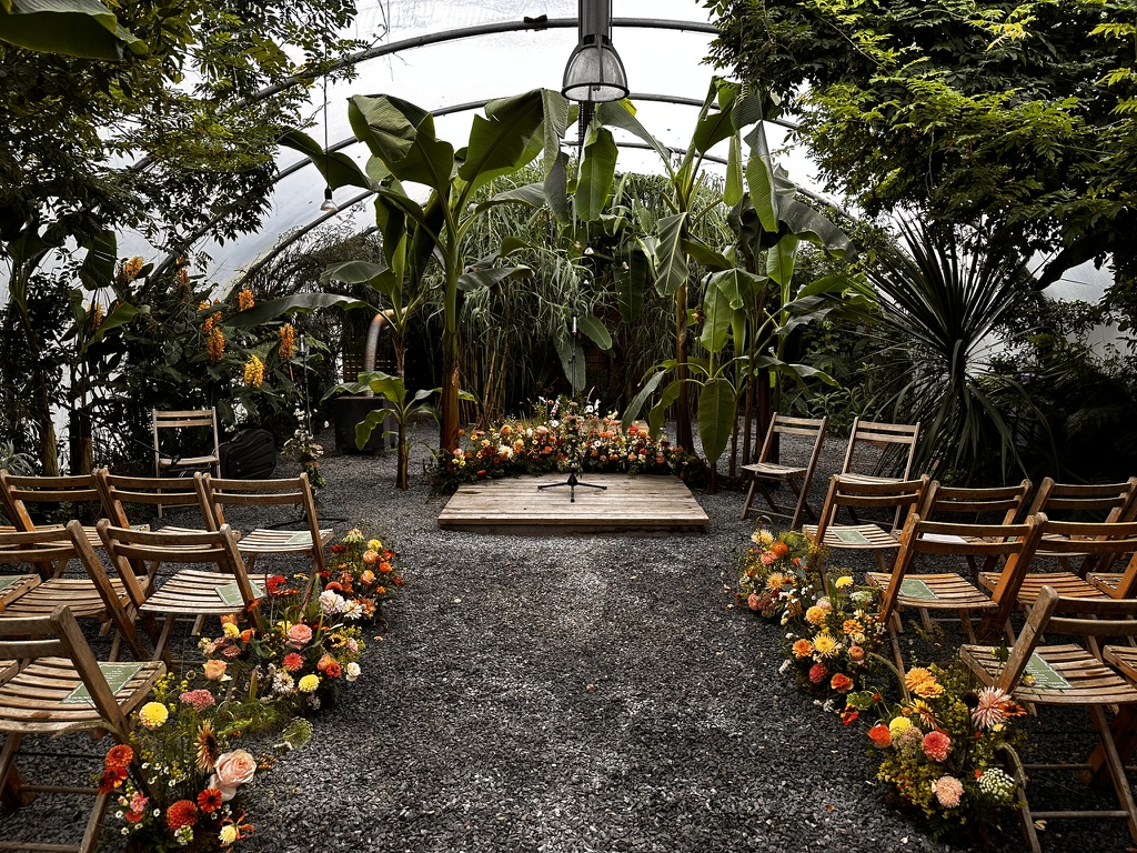 Wedding ceremony seating and flowers inside a tropical greenhouse