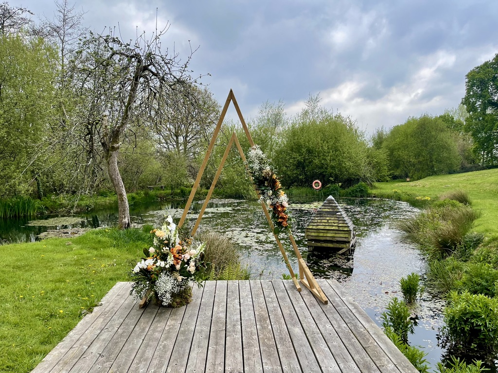 Floral wedding ceremony arch beside the lake