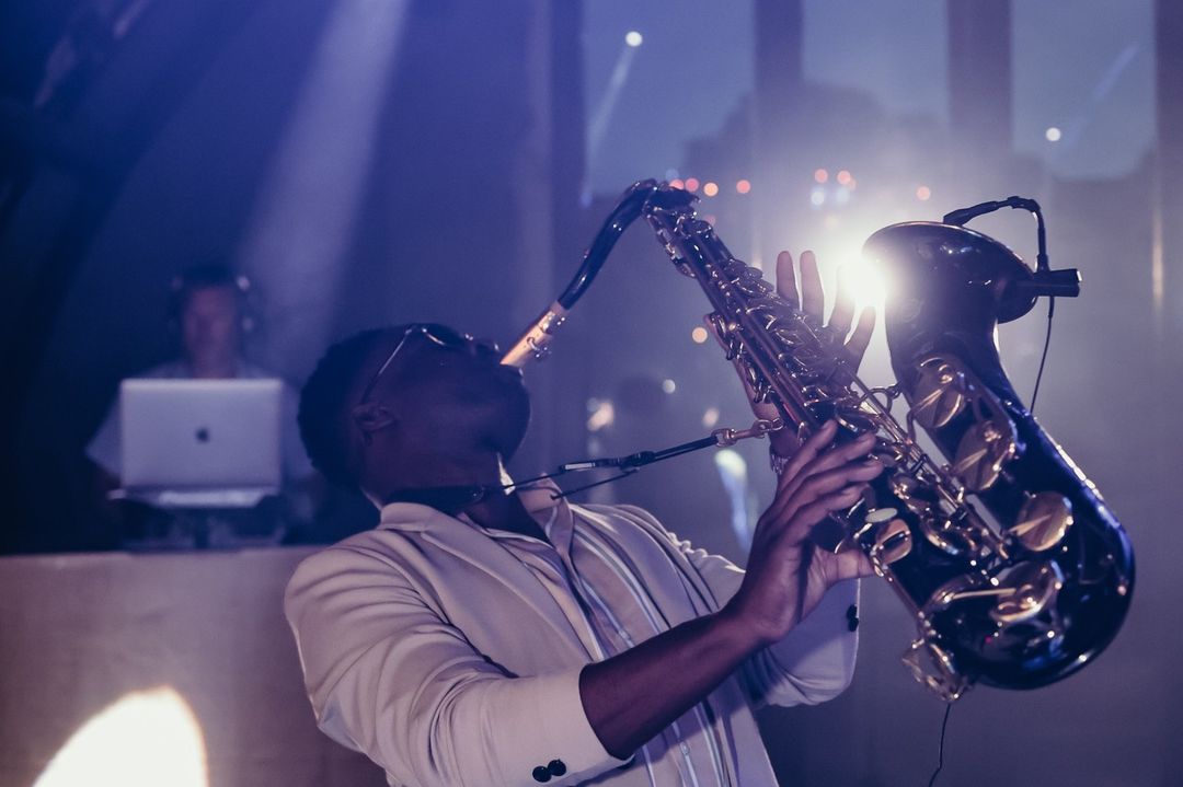 Saxophonist performing on the dance floor beneath stage lighting