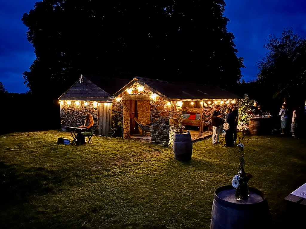 Guests enjoying an evening gathering beside a festoon-lit stone building
